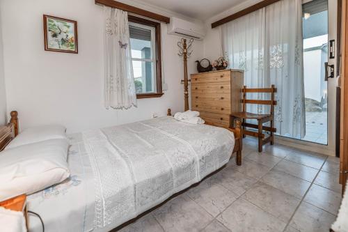 a bedroom with a bed and a chair and a window at Villa Hara Kiotari in Gennadi