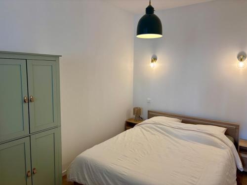 a bedroom with a white bed and a green cabinet at La Halte Beaujolaise in Belleville-en-Beaujolais