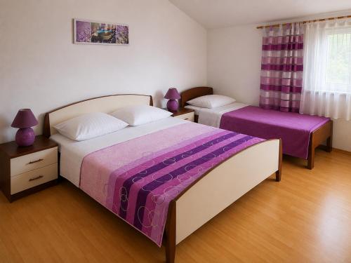 a bedroom with two beds with purple sheets at Apartments Tonći and Iris in Primošten