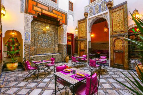 un restaurante con mesas y sillas púrpuras en una habitación en Dar Attajalli, en Fez