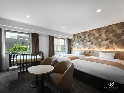 a hotel room with two beds and a table at Daiwa Roynet Hotel Oita in Oita