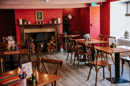 a restaurant with wooden tables and chairs and a fireplace at Northover Manor Hotel in Ilchester
