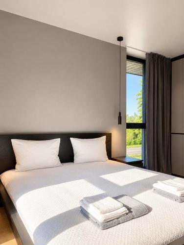 a bedroom with a large white bed with a window at Green Guest House in Sigulda