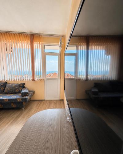 a living room with windows and a couch and a table at KITA - Rooms with Sea View in Sveti Vlas