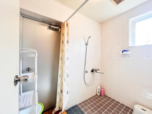 ein Badezimmer mit Dusche und Duschvorhang in der Unterkunft アトムハウス in Okinawa