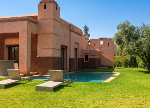 a house with a pool and two chairs in the yard at Elegant Villa in Marrakech with a Private Pool. in Douar bel Rhanodour