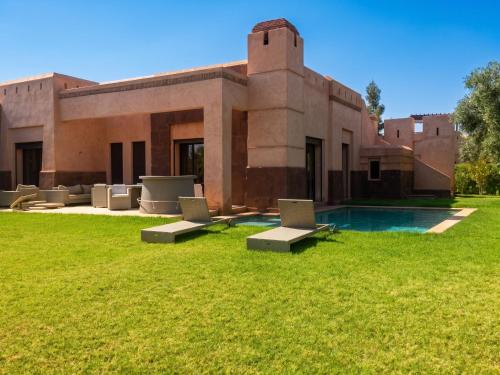 a building with a swimming pool in the grass at Elegant Villa in Marrakech with a Private Pool. in Douar bel Rhanodour