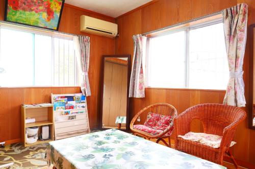 ein Schlafzimmer mit einem Tisch, zwei Stühlen und zwei Fenstern in der Unterkunft アトムハウス in Okinawa
