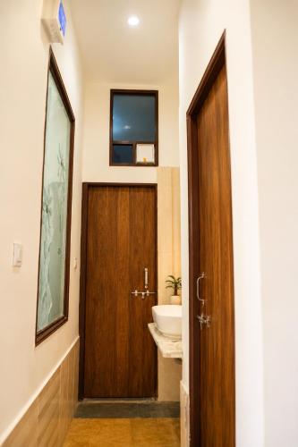 a bathroom with a wooden door and a sink at Hotel Atithya in Udaipur