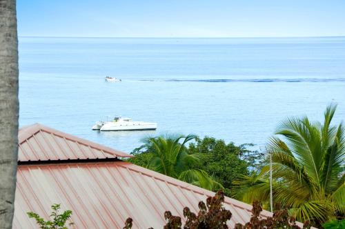 two boats in the ocean with trees and a building at Bungalow confortable avec vue mer à Bouillante in Bouillante