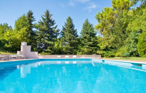 a large swimming pool with chairs and trees at Comfortable Apartment in Fabriano, 35 m² with Shared Pool in Fabriano
