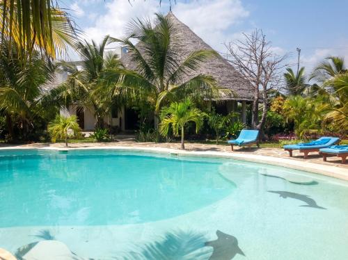 a swimming pool in front of a house with palm trees at Spacious accessible house in Watamu, shared pool in Watamu