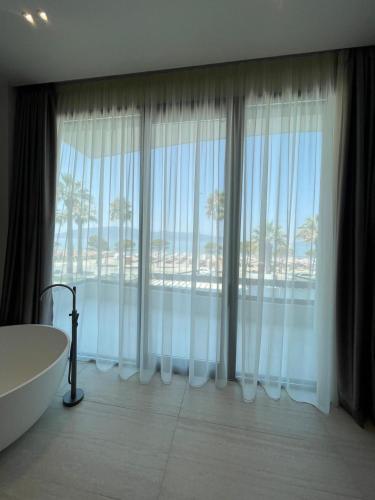 a bathroom with a tub and a large window at Marina Premium Beach Hotel & Apartments in Vlorë