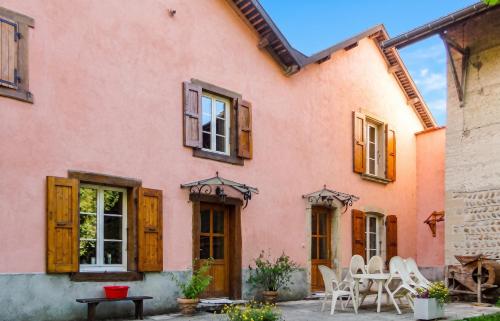 a pink house with wooden doors and chairs at Maison charmante à Chirens avec jardin clôturé in Chirens