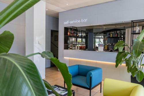a waiting room with a blue chair and a wine bar at Hotel Muralto Locarno in Locarno