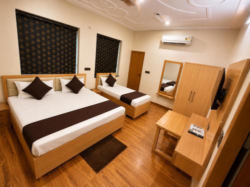 a hotel room with two beds and a mirror at Hotel Param INN in Gwalior