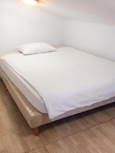 a bed with white sheets on a wooden floor at Appartement charmant à Roanne, terrasse in Roanne
