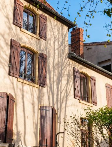 a building with brown shuttered windows and a tree at Appartement charmant à Roanne, terrasse in Roanne