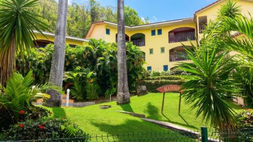 a yellow building with palm trees in front of a yard at Studio charmant à Sainte-Anne avec piscine privée, 25 m² in Sainte-Anne