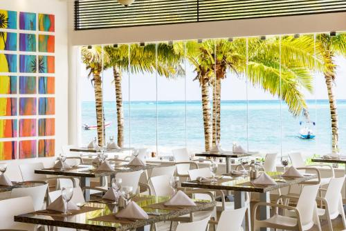 a restaurant with palm trees and the ocean at The Reef Coco Beach Resort & Spa- Optional All Inclusive in Playa del Carmen