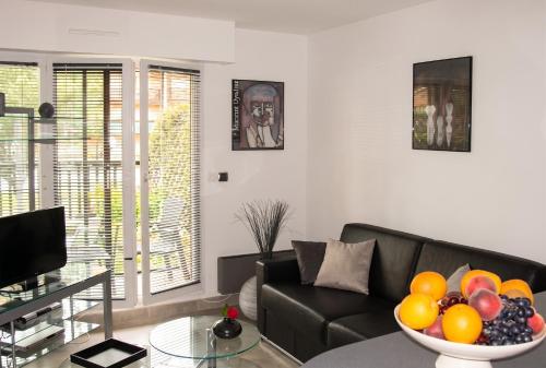a living room with a couch and a bowl of fruit on a table at Studio charmant à Villers-sur-Mer avec terrasse - 33 m² in Villers-sur-Mer
