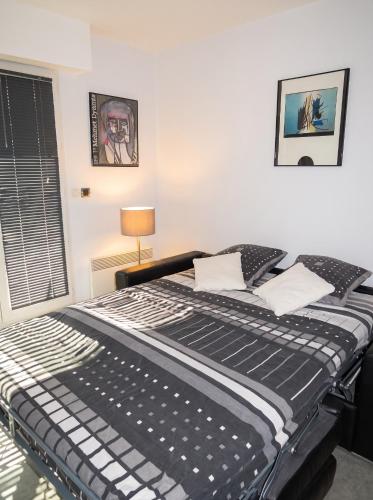 a black and white bed in a room with a window at Studio charmant à Villers-sur-Mer avec terrasse - 33 m² in Villers-sur-Mer
