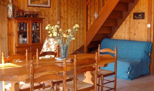 a dining room with a table and a blue couch at Charmante maison avec piscine privée à Orsanco - 70 m² in Orsanco