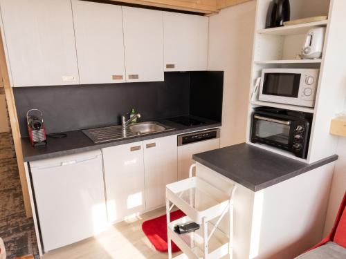 a kitchen with white cabinets and a sink and a microwave at Studio chaleureux à Aime la Plagne 25 m² en montagne in Aime-La Plagne