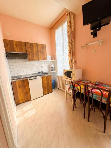 a kitchen with wooden cabinets and a table with chairs at Studio confort à Néris-les-Bains - 18 m² avec jardin in Néris-les-Bains