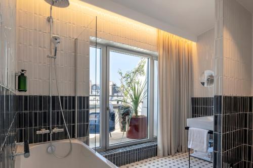 a bathroom with a bath tub and a window at Urban Hive Paris in Paris
