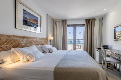 ein Schlafzimmer mit einem großen weißen Bett und einem Schreibtisch in der Unterkunft Hoposa Niu in Cala de Sant Vicent