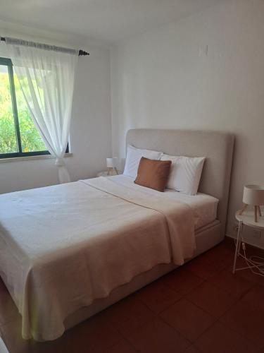 a bedroom with a large white bed with a window at Solar Pinheiros RC in Vilamoura