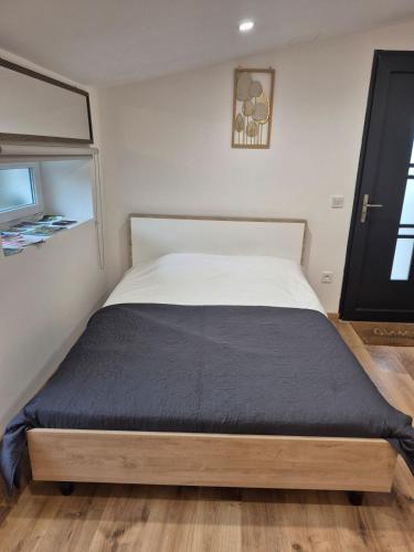 a bedroom with a large bed with a black blanket at Studio chic meublé et lumineux in Chauray
