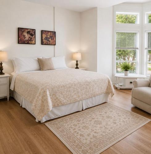 a white bedroom with a bed and two windows at Seaview Executive Home in Ladysmith
