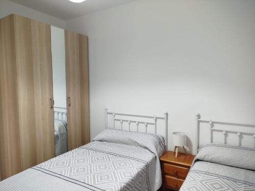 a bedroom with two beds and a dresser with a lamp at Aires de Chipiona Apartamento A in Chipiona