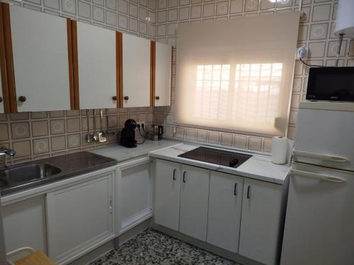 a kitchen with white cabinets and a sink and a refrigerator at Aires de Chipiona Apartamento A in Chipiona