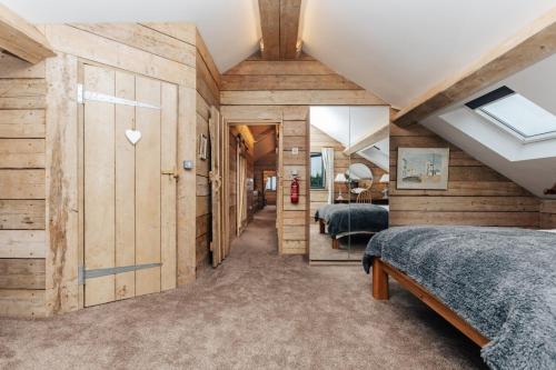 a bedroom with wooden walls and two beds at Owl Barn in Little Milton