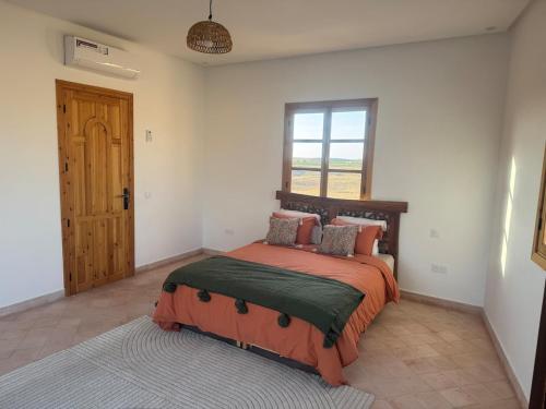 a bedroom with a bed and a window and a door at Villa tawarda in Oumnas