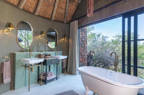 a bathroom with a tub and two sinks and a large window at Last Word Makanyane in Laastepoort