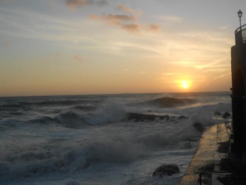 a sunset over the ocean with waves crashing on the shore at Apartment Da Pupetta in Sori