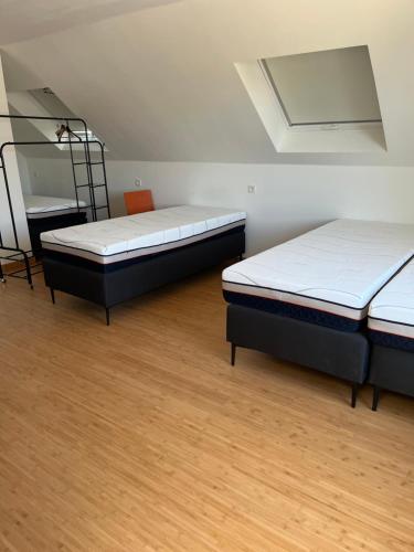 two beds in a room with wooden floors at Guesthouse Kriebeke in Tielt