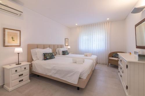 a bedroom with a large white bed and a dresser at Bia in Almancil