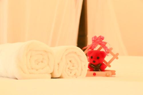 a white towel with a red teddy bear next to a toy at Parrot Perch Villa Dickwella in Dickwella