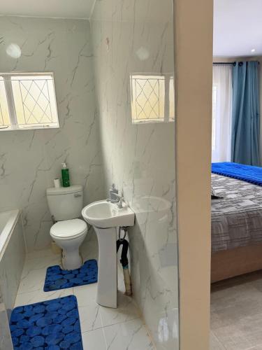 a bathroom with a sink and a toilet and a bed at Selah House in Harare