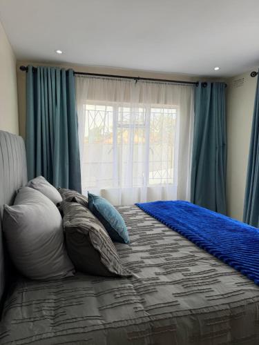 a bedroom with a bed with pillows and a window at Selah House in Harare