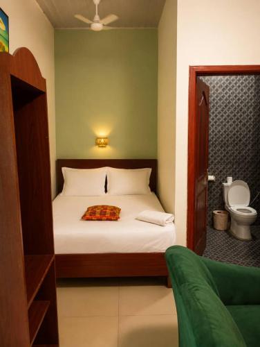 a bedroom with a bed and a bathroom with a toilet at Lois Beach Resort in Nyanyanu