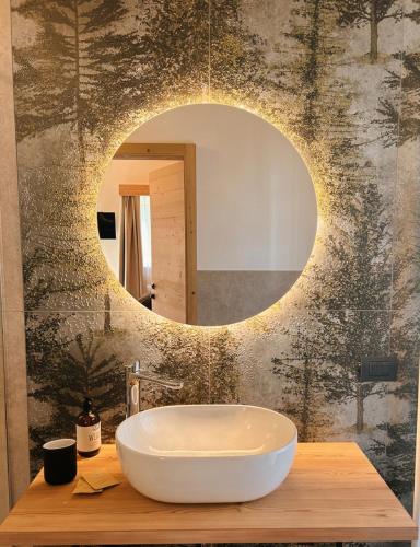 a bathroom with a round mirror and a sink at B&B Te Nìf in Predazzo