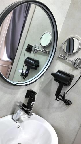 a mirror above a bathroom sink with a camera at Elegance Hotel Osh in Osh