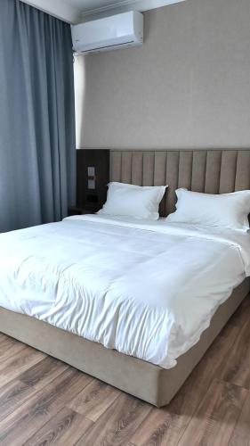 a large white bed with white sheets and pillows at Elegance Hotel Osh in Osh