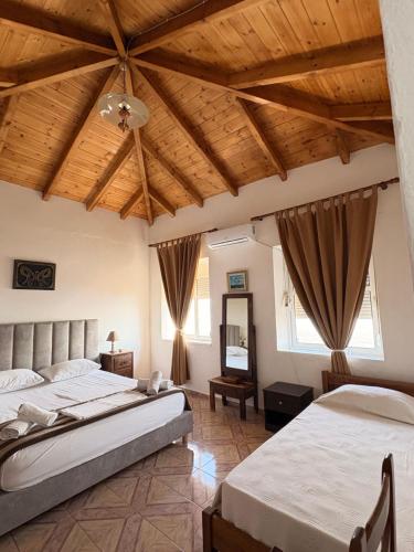 two beds in a bedroom with wooden ceilings at Q Bay Apartments in Qeparo